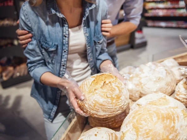 Couple examining a round loaf of bread in a bakery aisle