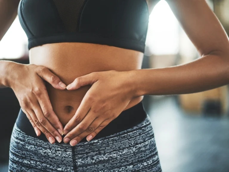 Woman holds her hands in a heart shape across her stomach
