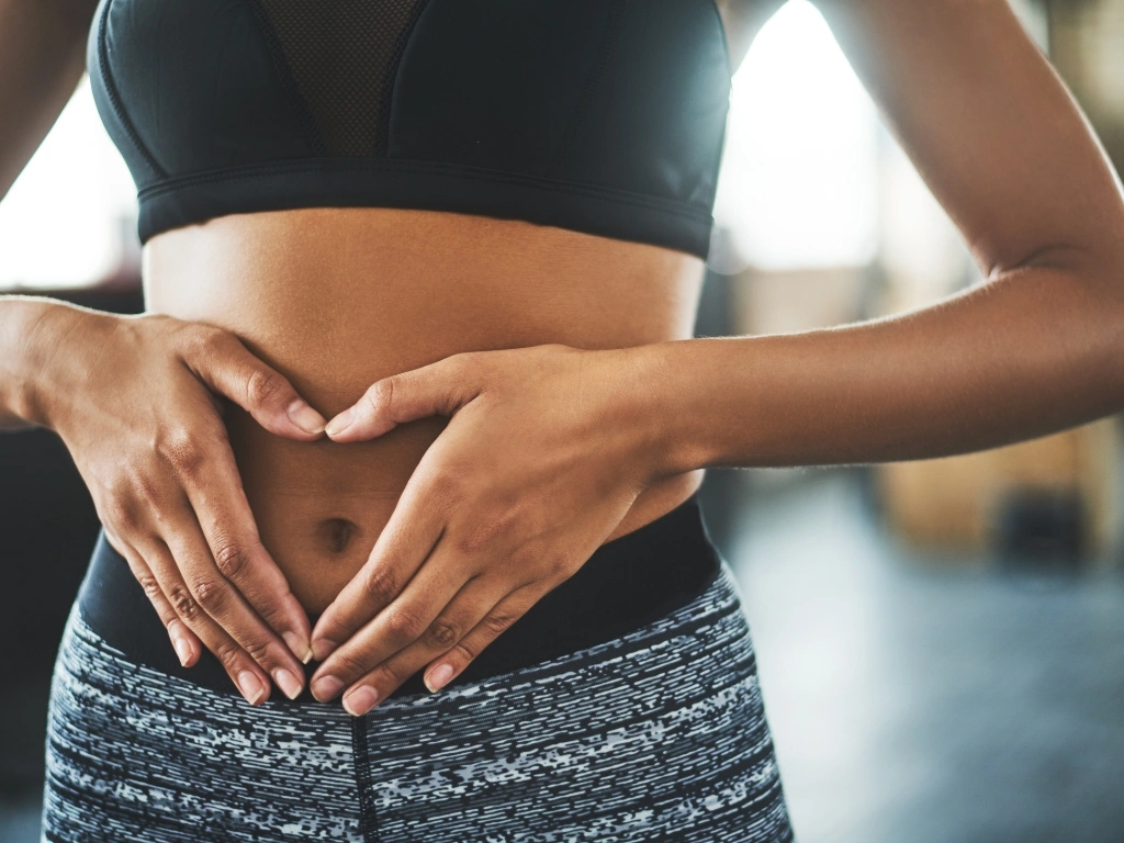 Woman holds her hands in a heart shape across her stomach