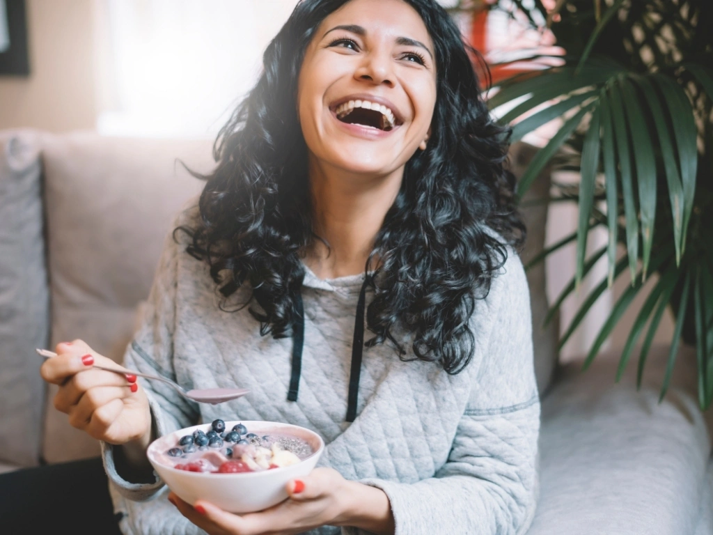 Woman happily eating a bowl of yogurt with berries