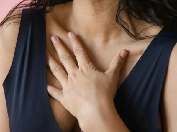 Woman in a blue top with her hand resting on her chest