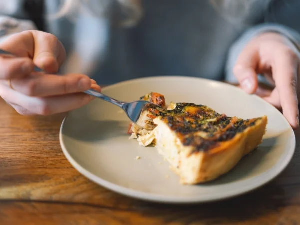 Person using a fork to get a slice of vegetable quiche