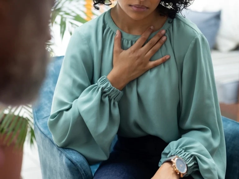 A woman clutching her chest due to a GERD flare-up