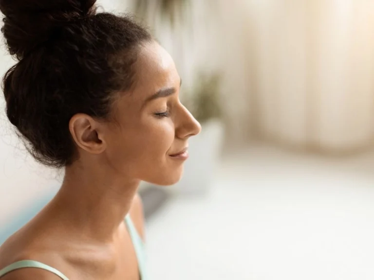 A woman with eyes closed, feeling relief while healing IBS through long-term care