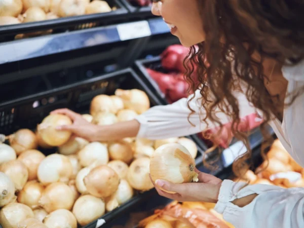 Woman selecting onions from the produce aisle at a grocery store