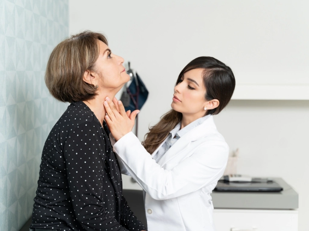 A doctor examining an older woman for thyroid issues