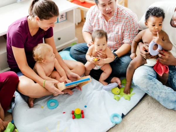 New moms and dad, sitting with their children, playing with toys