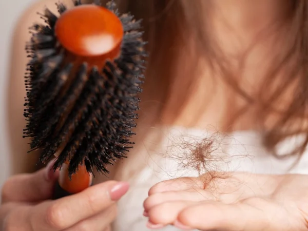 A woman holding a brush and loose strands of hair