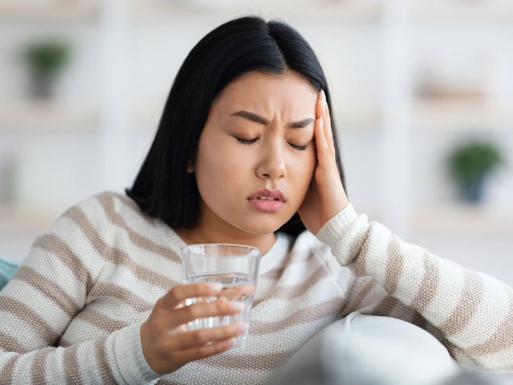 A woman holding her head while experiencing nausea