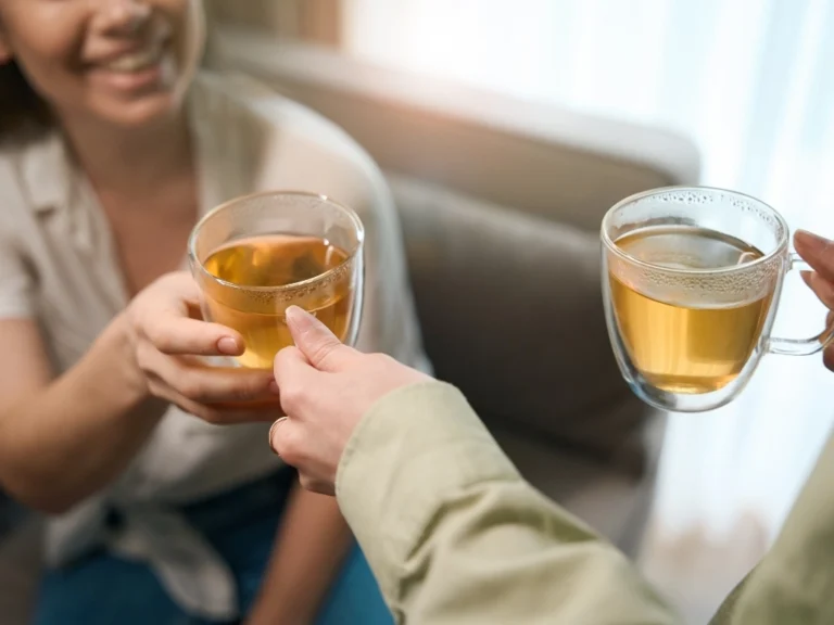 Two people happily bonding over cups of herbal tea, a natural remedy for IBS