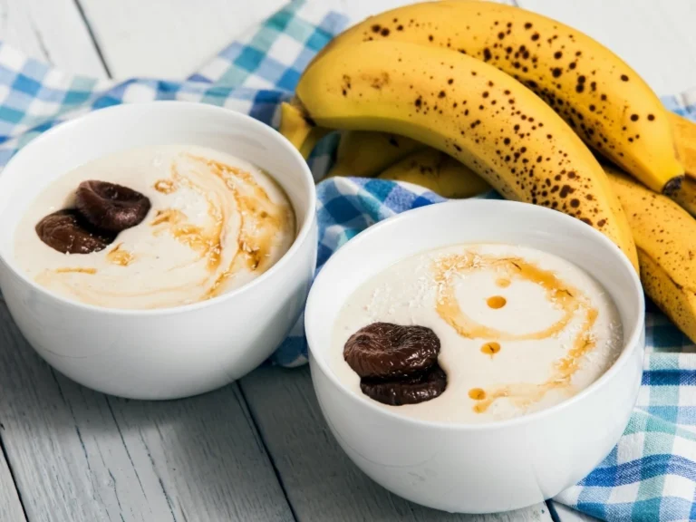 Two bowls of creamy yogurt topped with honey and dates, served beside ripe bananas