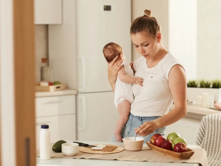 A mother cooking breakfast while holding a baby