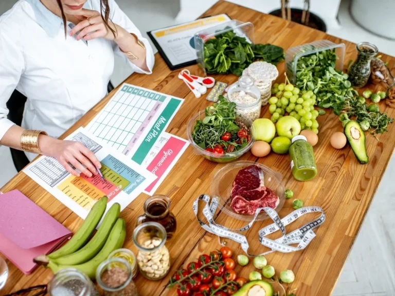 Dietitian writing a meal plan on a desk surrounded by healthy foods and sketches about nutrition