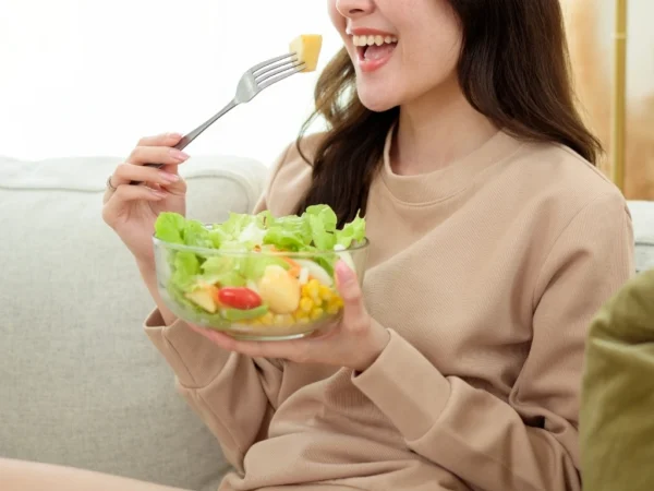 Woman eating a bowl of vegetable salad at home