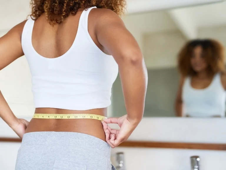 Woman measuring her weight in front of a mirror