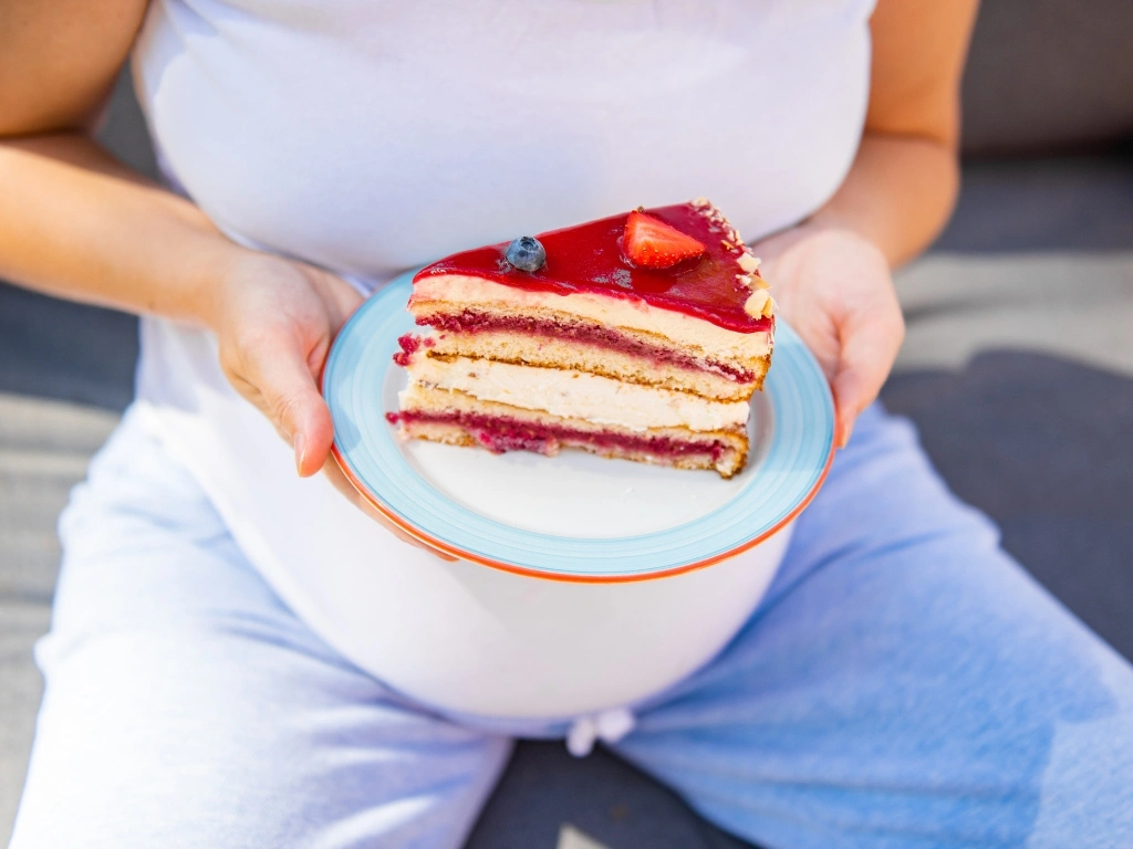Pregnant woman holding a plate of layered berry cake