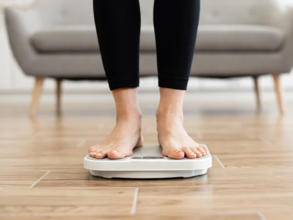 Person weighing self on digital scale in living room