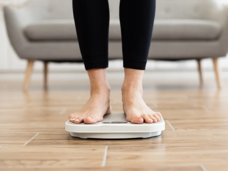 Person weighing self on digital scale in living room