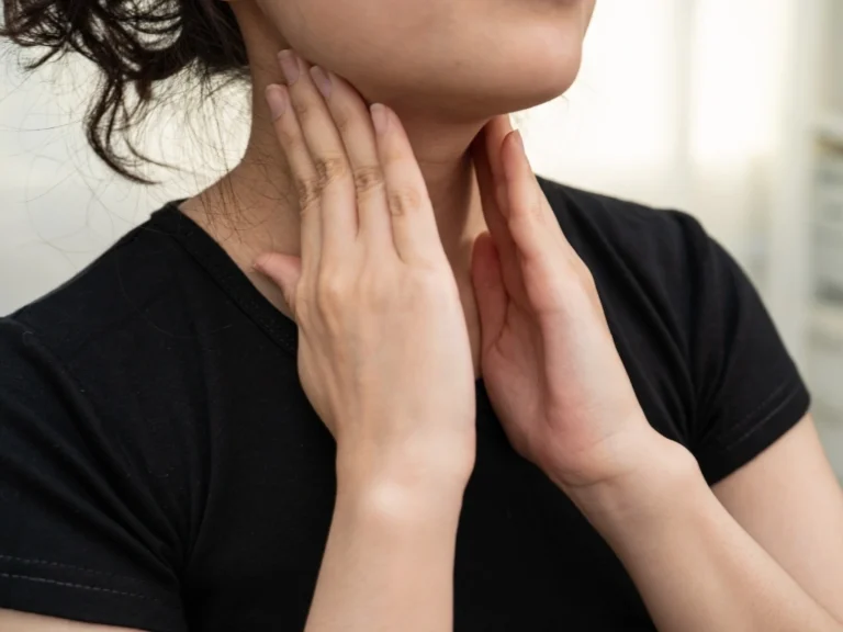 Woman touching her throat due to thyroid discomfort.