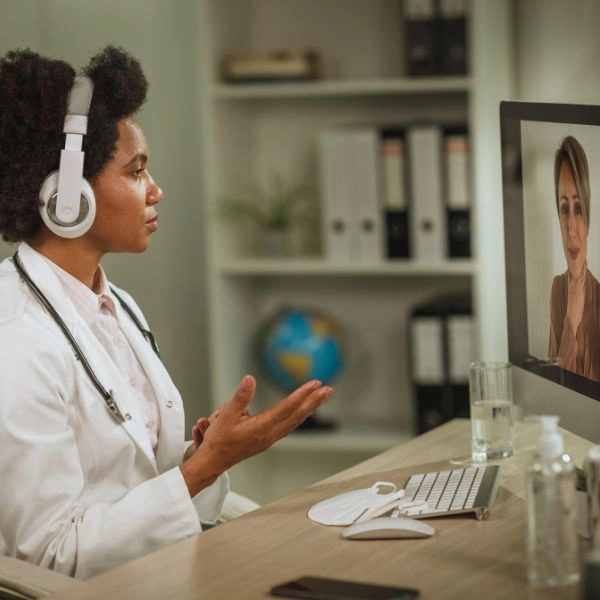 Celiac disease nutritionist wearing headphones conducting a telehealth video consultation with a patient on a computer