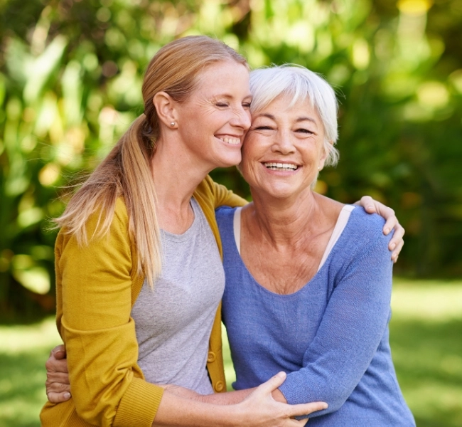 Two women hugging each other and smiling with eyes closed