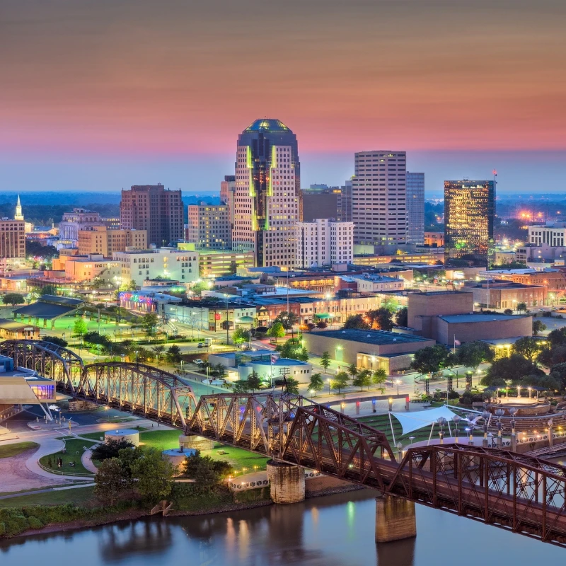 The downtown area of Shreveport, Louisiana, at dusk, with the Texas Street Bridge spanning the Red River in the foreground,